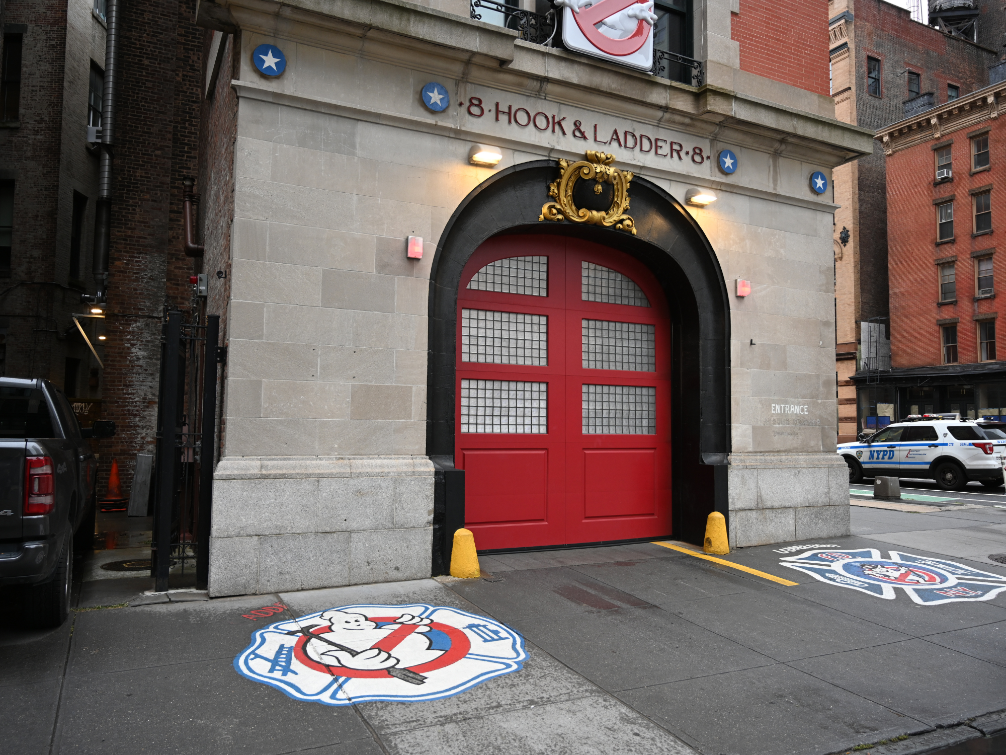Red doors of fire station 8 Hook & Ladder with Ghostbusters logos on the pavement, located in New York.
