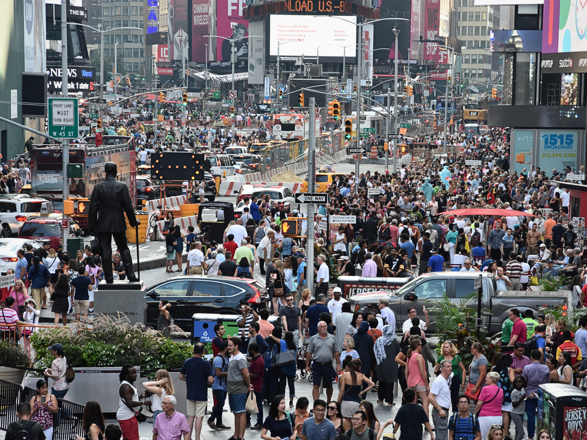 Crowded Times Square in New York, filled with people, cars, and bright advertisements.