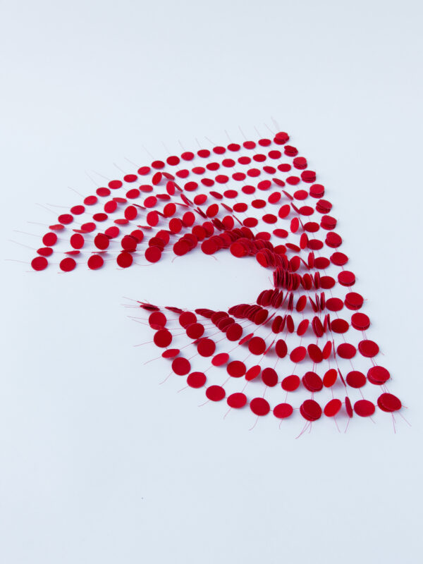 Red circular lace pieces arranged in a dynamic, flowing pattern on a white background, titled "BETWEEN SPACES.