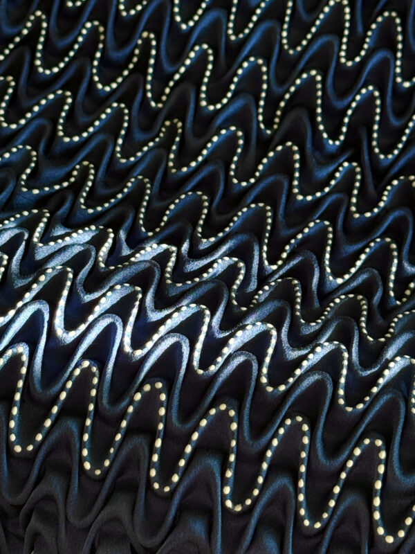 Textured fabric with wavy patterns and metallic accents in shades of blue and black.