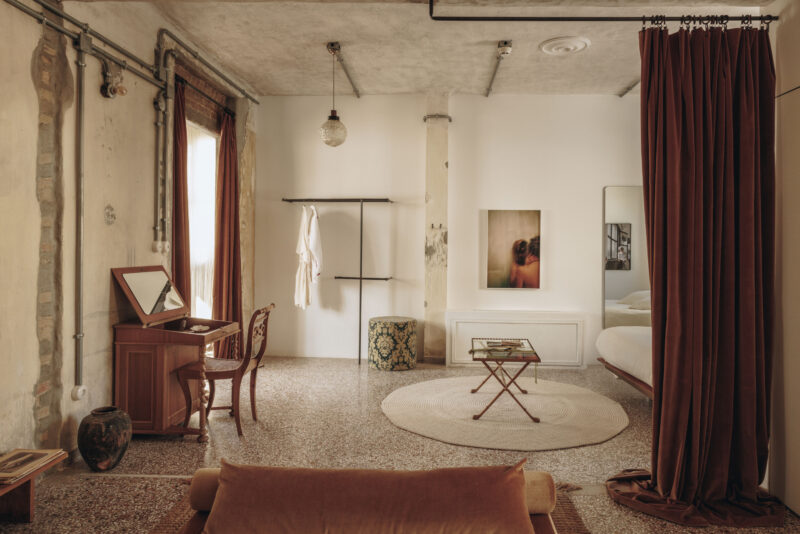 Stylish interior of a room featuring a vanity, a round rug, and a bed, with warm tones and artistic decor.