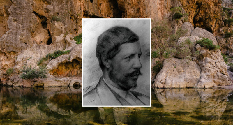 Black and white portrait of a man framed against a serene rocky landscape with water reflecting the cliffs.