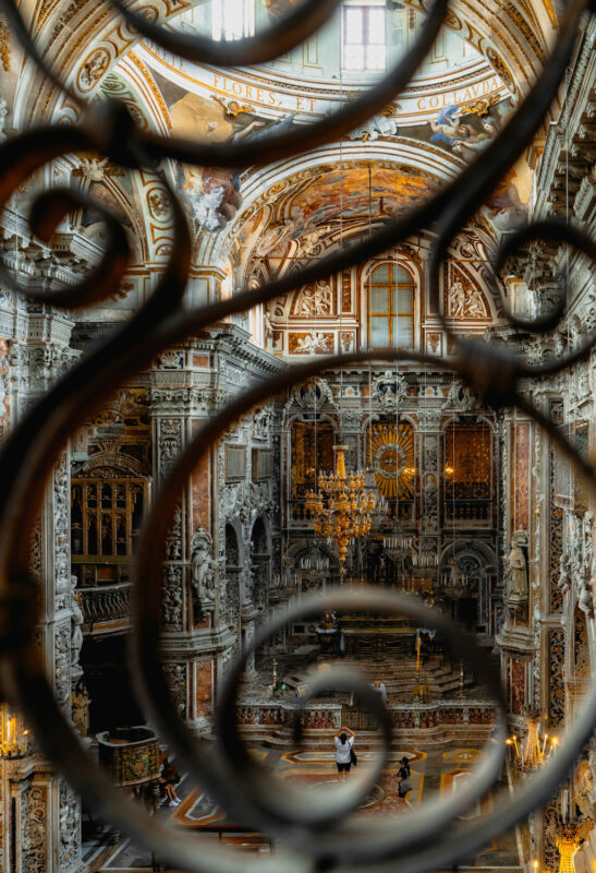 Intricate interior of a grand church in Palermo, viewed through ornate wrought iron, showcasing detailed architecture and ...