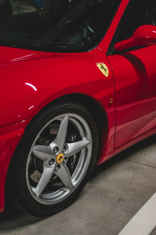 Close-up of a red Ferrari sports car, highlighting the silver wheel and iconic prancing horse logo.